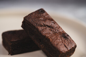 Close-up of Chocolate brown on a plain ceramic tile with soft natural light and a neutral stone background.