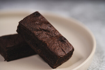 Close-up of Chocolate brown on a plain ceramic tile with soft natural light and a neutral stone background.