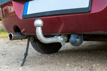 A close-up of the tow bar mounted on the rear of a passenger car. The metal tow ball and trailer...