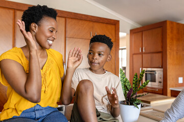 Mother and son enjoying playful moment together in modern kitchen at home