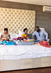 Family packing suitcase on bed, preparing for vacation with excitement and smiles