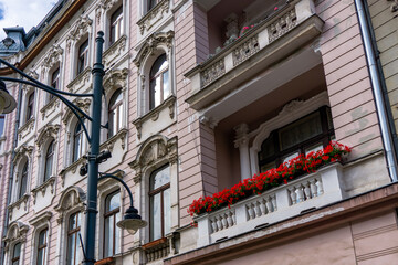 Tenement house in Ł&oacute;dź with decorative balcony, balustrade and red flowers, historic Art Nouveau architecture, detailed facade elements.