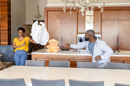 Couple playfully unpacking in modern kitchen, smiling and enjoying new home - Powered by Adobe