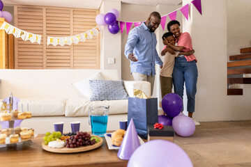 Family celebrating birthday at home, hugging and smiling with party decorations