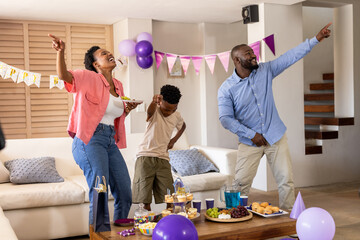 Dancing joyfully at home, family celebrating birthday with snacks and decorations