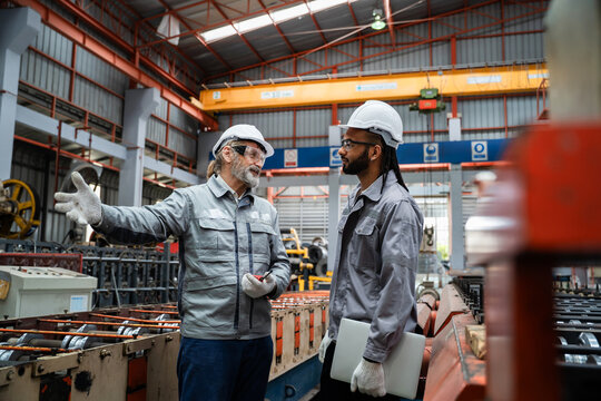 Two men in a factory discussing something - Powered by Adobe