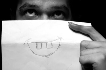 Covering Sad Face with Paper Showing a Smiling Mouth – Concealing Emotions Concept