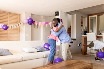 Family celebrating birthday at home, hugging with joy and festive decorations