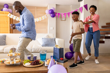 Celebrating birthday at home, family dancing with festive decorations together