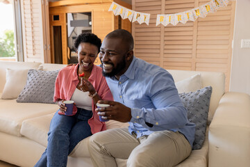 Celebrating birthday, happy couple enjoying coffee and laughter on cozy sofa