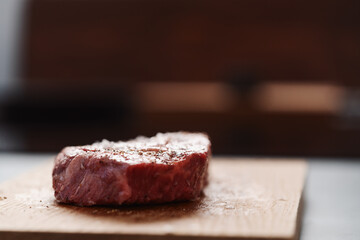 Raw ribeye steak spiced and ready to cook on oak board