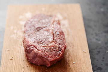Raw ribeye steak spiced and ready to cook on oak board