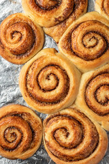 Freshly baked cinnamon rolls on a baking sheet top view. Making cinnamon rolls process. Cinnabon preparation