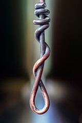 Twisted, patinated copper wire in a dark industrial setting, close-up view