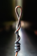 Twisted, patinated copper wire in a dark industrial setting, close-up view
