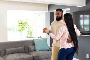 African American couple dancing together at home, enjoying joyful moment