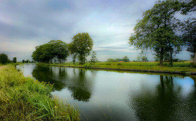 A beautifully serene river scene showcasing vibrant greenery and a reflective surface beneath cloudy skies