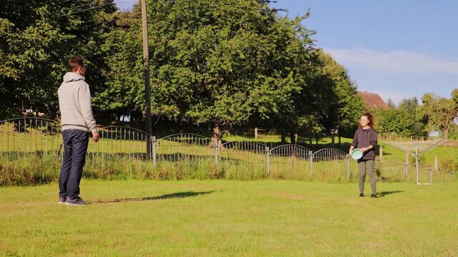 A couple relishes a bright day outdoors, throwing a frisbee back and forth in their spacious backyard. They share laughter and smiles as they enjoy quality time together