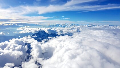 Majestic aerial view showcasing snow-capped mountain peaks piercing through fluffy clouds under a vibrant blue sky