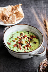 Enjoy a vibrant green soup topped with crispy ingredients, paired