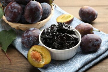Dried prunes, fresh plums and green leaf on wooden table, closeup