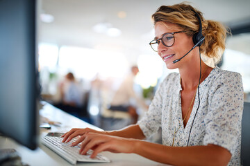 Agent providing customer service while using a headset at a busy office desk