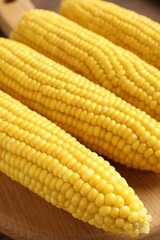 Tasty boiled corncobs on wooden table, closeup