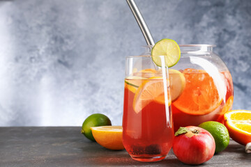 Punch and fresh fruits on grey table, space for text. Refreshing drink