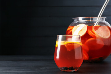 Fruity punch on black wooden table, space for text. Refreshing drink