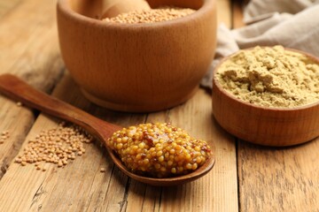 Different types of mustard on wooden table, closeup