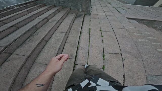 Action camera POV shot of two unrecognizable parkourists in streetwear freerunning in urban environment practicing parkour skills together