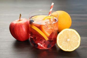 Tasty punch in glass and fresh fruits on wooden table, closeup. Refreshing drink