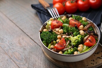 Delicious salad with shimeji mushrooms, chickpeas, tomatoes and broccoli on wooden table, closeup. Space for text