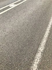 Fototapeta premium A road with a white line down the middle. The road is wet. There are some rocks on the road
