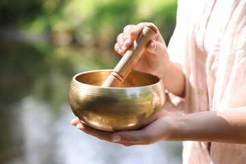 Woman with singing bowl in nature, closeup