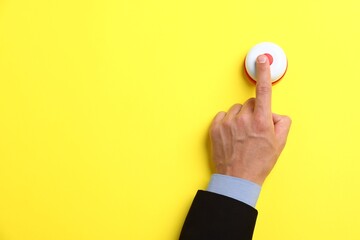 Man pressing button on yellow background, top view. Space for text