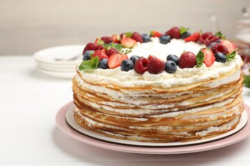 Delicious crepe cake with fresh berries on white table, closeup