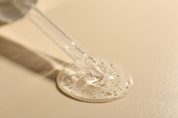 Taking cosmetic product with pipette on beige background, closeup