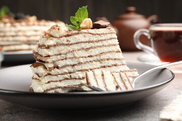 Piece of tasty crepe cake with cocoa powder, chocolate and nuts served on light table, closeup