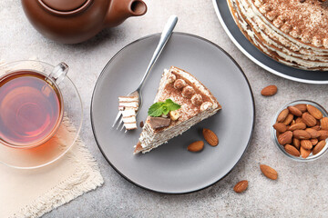 Piece of tasty crepe cake with cocoa powder, chocolate and nuts served on light table, flat lay