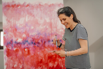 Female artist painting abstract modern art on canvas, enjoying creative process