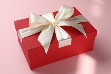 Beautiful gift box with bow on pink background