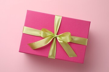 Beautiful gift box with bow on pink background, top view