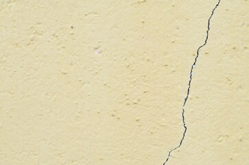vertical crack runs along a weathered, pale yellow wall, effectively illustrating the need for repair, maintenance, and home improvement.