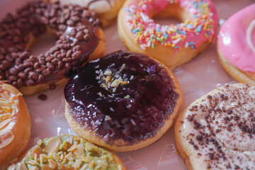 A person's hand takes a delicious donut from a box of twelve assorted pastries with colorful toppings.	