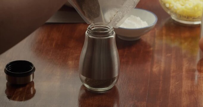 A woman pours freshly ground black allspice into a special pepper shaker.