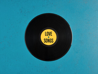 Vinyl record with yellow label showing love songs writing on blue background