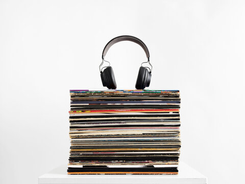 Headphones resting on stack of vinyl records representing music listening and collecting hobby