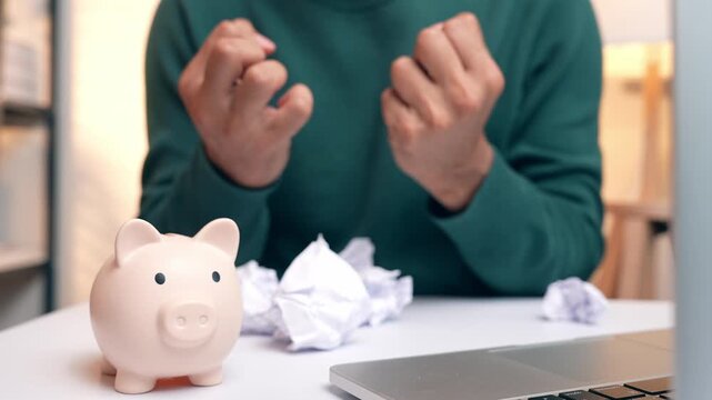 A person crumpling debt bills beside a piggy bank, expressing sorrow and despair, symbolizing financial burden, money stress, emotional struggle, poor debt management, and the need for change.
