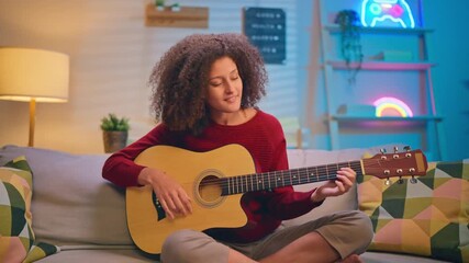 Latina beautiful woman playing guitar in living room at home. 
